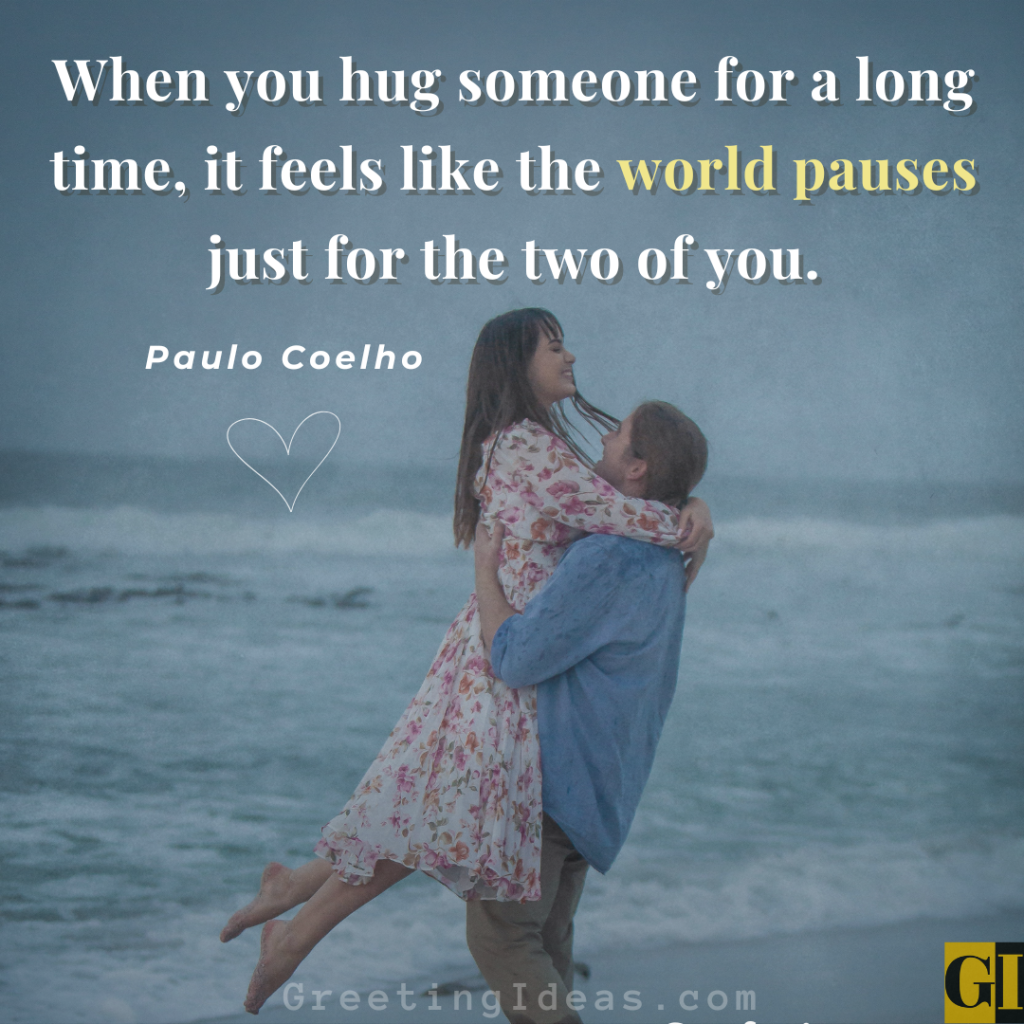Paulo Coelho love quote about hugging over romantic couple embracing on beach at sunset - world pauses for two